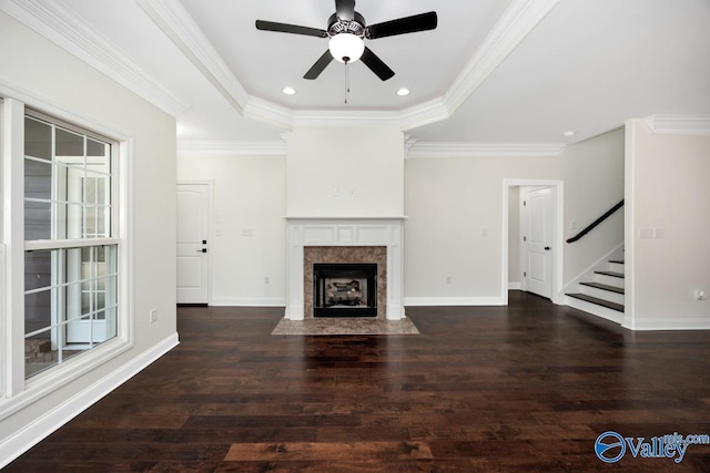 unfurnished living room featuring a tile fireplace, a wealth of natural light, ornamental molding, dark hardwood / wood-style flooring, and a raised ceiling