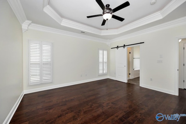 empty room featuring crown molding, ceiling fan, a raised ceiling, dark hardwood / wood-style flooring, and a barn door