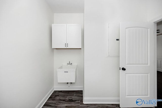 laundry room with sink, electric panel, and dark hardwood / wood-style floors