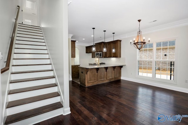 staircase featuring crown molding, wood-type flooring, and a chandelier