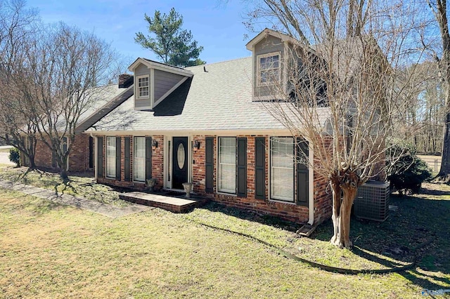 new england style home featuring a front lawn, cooling unit, and brick siding