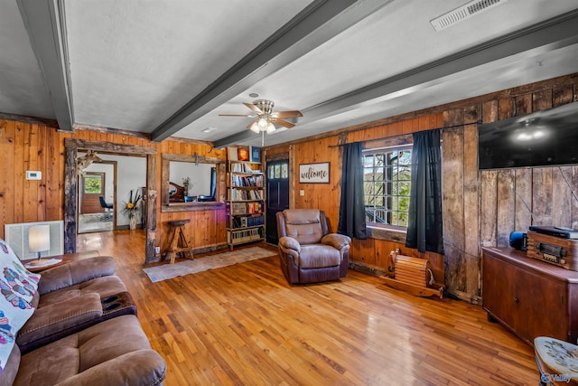 living room featuring beam ceiling, wooden walls, ceiling fan, and hardwood / wood-style flooring