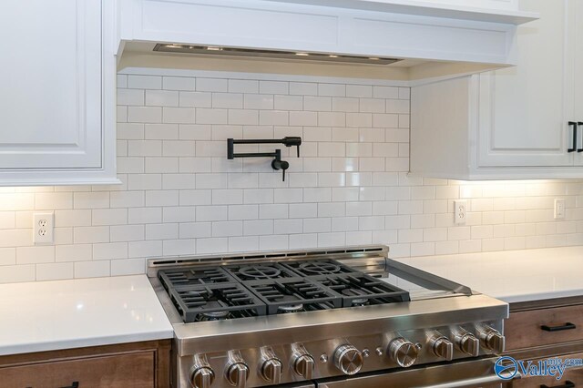 kitchen featuring tasteful backsplash, gas range, and white cabinets