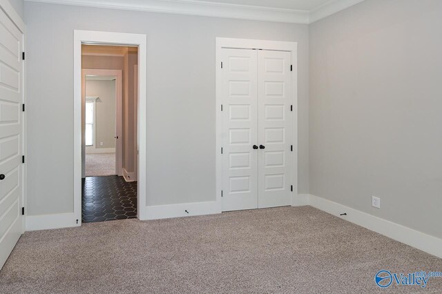 unfurnished bedroom featuring ornamental molding, a closet, carpet flooring, and baseboards