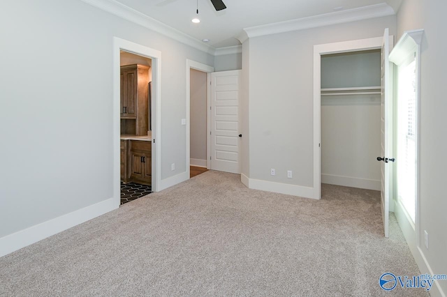 unfurnished bedroom featuring crown molding, carpet, ensuite bathroom, a closet, and ceiling fan