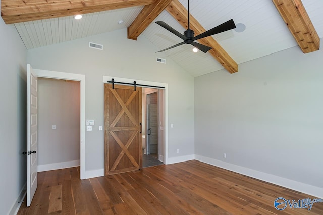 unfurnished bedroom with lofted ceiling with beams, a barn door, dark wood-style flooring, visible vents, and baseboards