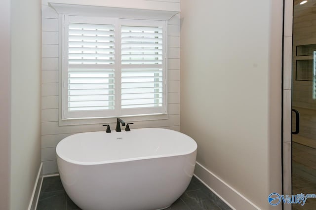 bathroom featuring a soaking tub and baseboards