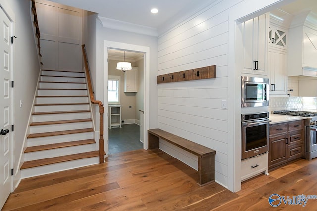 mudroom with ornamental molding, recessed lighting, wood walls, and wood finished floors