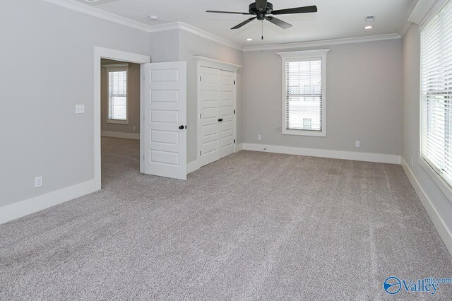 unfurnished bedroom with multiple windows, light carpet, and crown molding