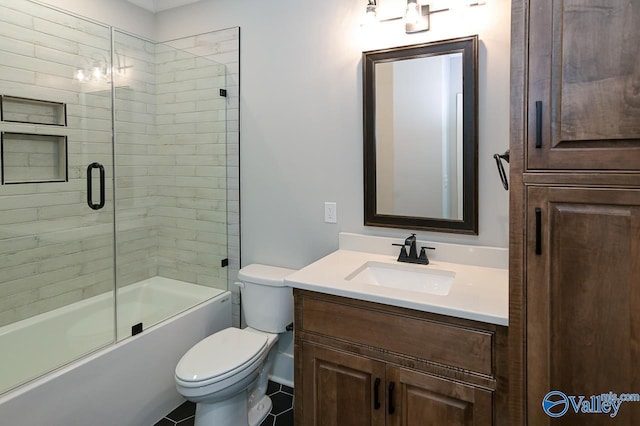 bathroom featuring toilet, combined bath / shower with glass door, and vanity