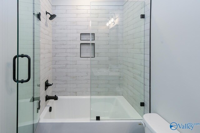 bathroom featuring bath / shower combo with glass door and toilet