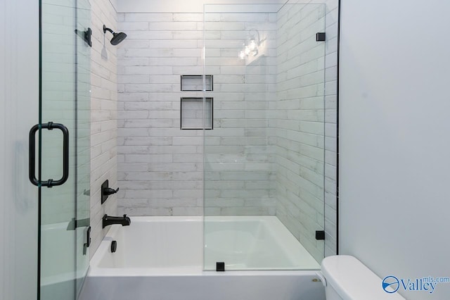 bathroom featuring toilet and shower / bath combination with glass door