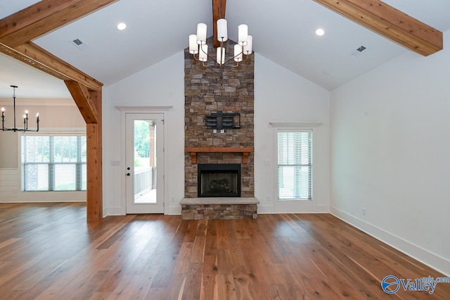 unfurnished living room with an inviting chandelier, visible vents, beam ceiling, and a stone fireplace