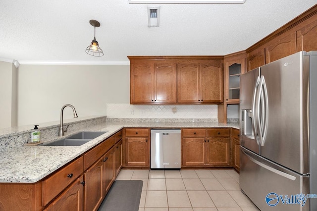 kitchen featuring brown cabinetry, ornamental molding, stainless steel appliances, and a sink