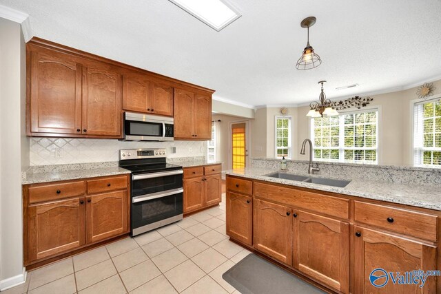 kitchen with backsplash, a sink, crown molding, brown cabinetry, and appliances with stainless steel finishes