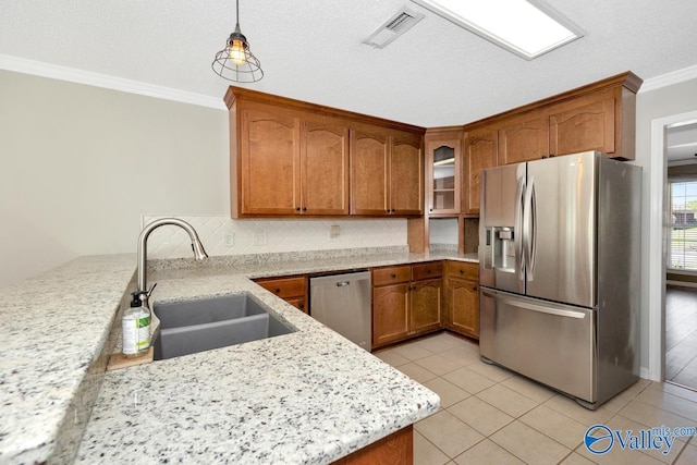 kitchen with stainless steel appliances, a sink, visible vents, brown cabinets, and ornamental molding