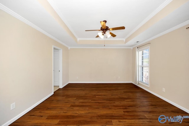 empty room with a raised ceiling, wood finished floors, crown molding, baseboards, and ceiling fan