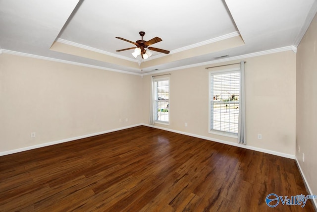 empty room with a ceiling fan, a raised ceiling, baseboards, dark wood-type flooring, and visible vents