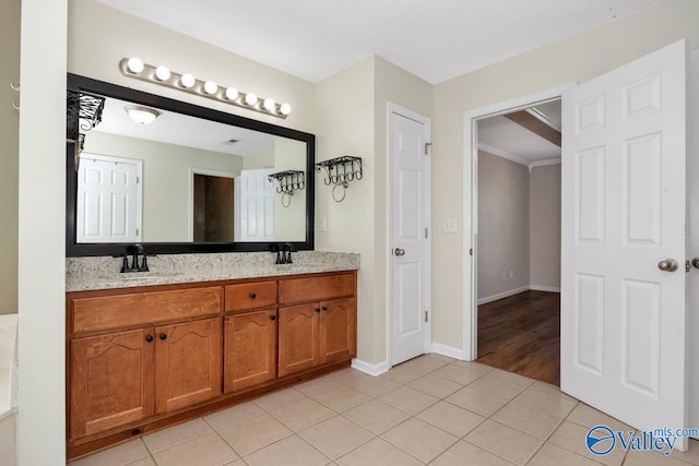 full bathroom with double vanity, tile patterned floors, baseboards, and a sink