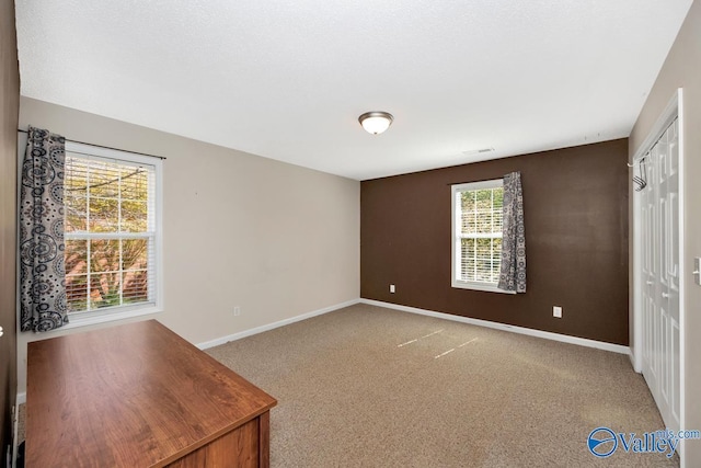 unfurnished bedroom featuring baseboards, carpet floors, and a closet