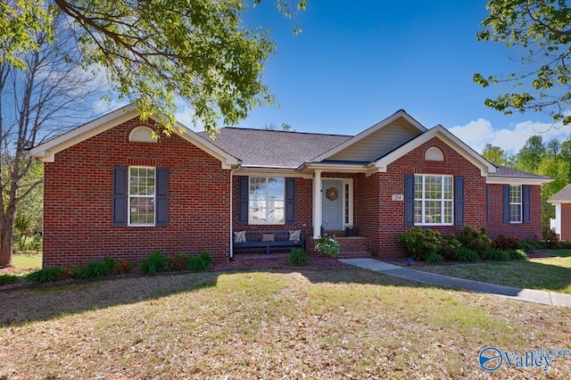 ranch-style home featuring brick siding, a shingled roof, and a front lawn