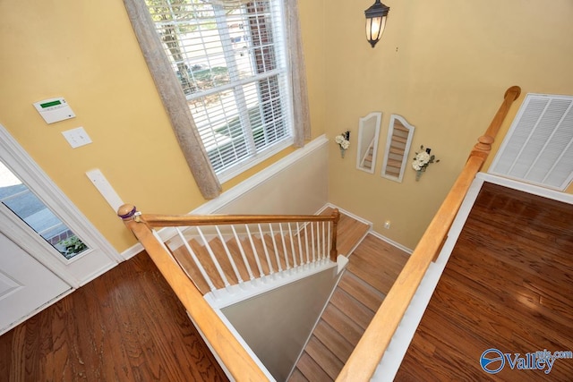 stairway featuring wood finished floors, visible vents, and baseboards