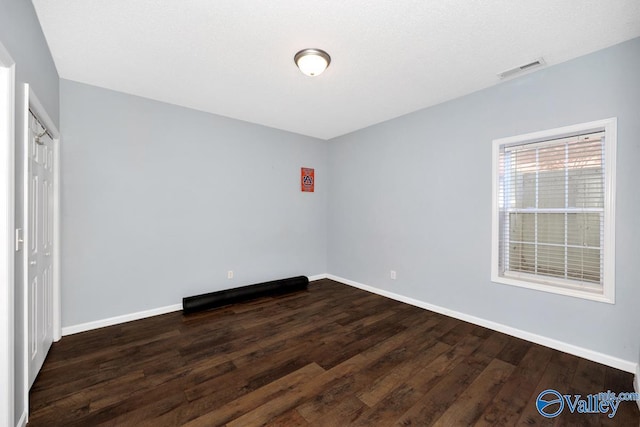 unfurnished room with visible vents, baseboards, and wood finished floors
