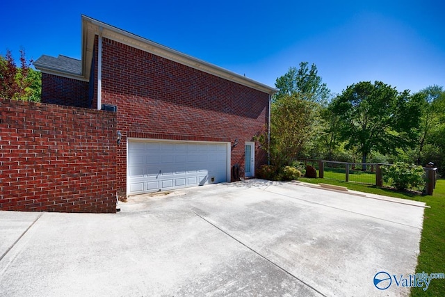 view of home's exterior featuring fence, driveway, and brick siding