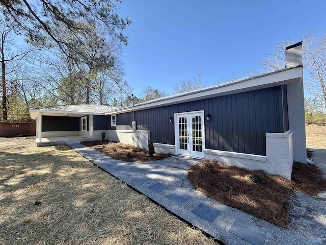 exterior space featuring french doors, a chimney, and brick siding