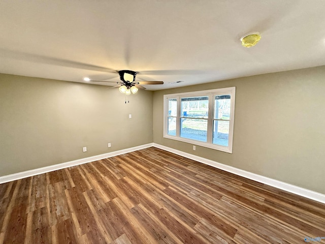 unfurnished room featuring a ceiling fan, dark wood finished floors, visible vents, and baseboards