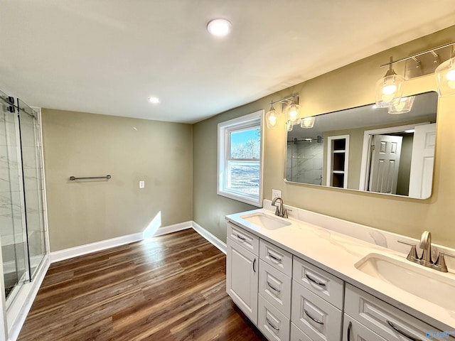 full bath featuring tiled shower, a sink, baseboards, and wood finished floors