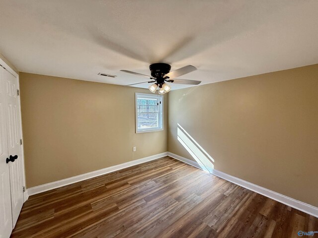 unfurnished bedroom with visible vents, baseboards, dark wood finished floors, ceiling fan, and a closet