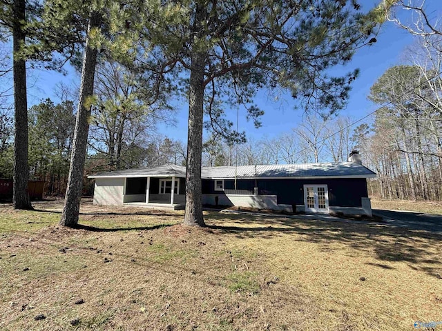 rear view of house with french doors and a lawn