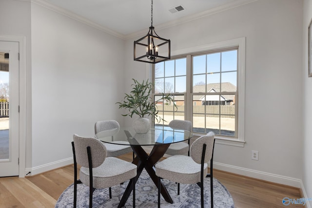 dining room with visible vents, baseboards, ornamental molding, and light wood finished floors