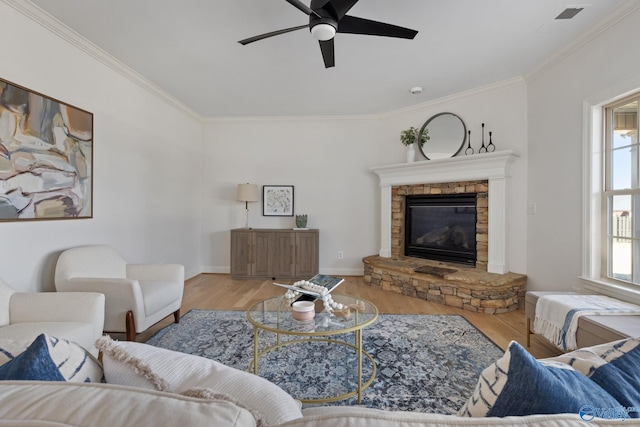 living room with a stone fireplace, wood finished floors, and crown molding