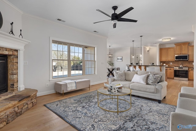 living room with crown molding, visible vents, and light wood finished floors