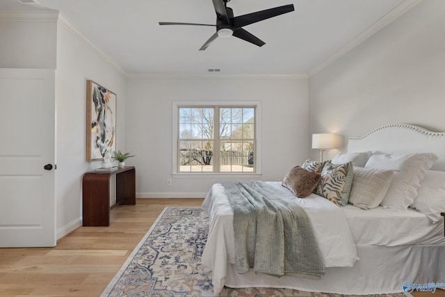 bedroom with a ceiling fan, baseboards, visible vents, crown molding, and light wood-type flooring