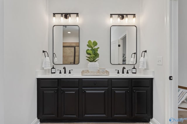 full bath featuring a sink, baseboards, and double vanity