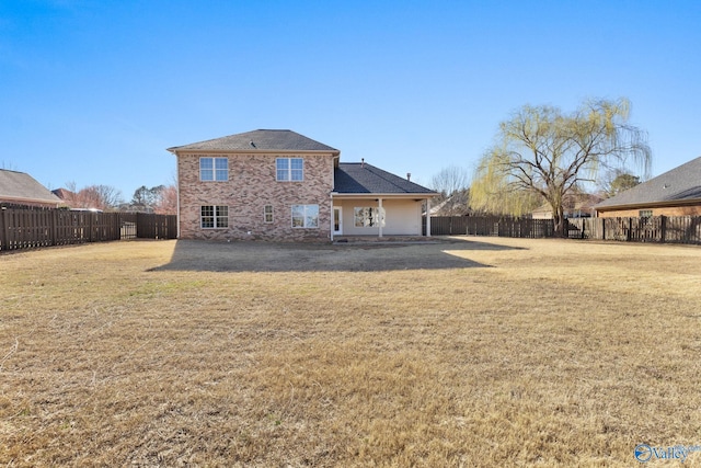 rear view of house featuring brick siding, a lawn, and a fenced backyard