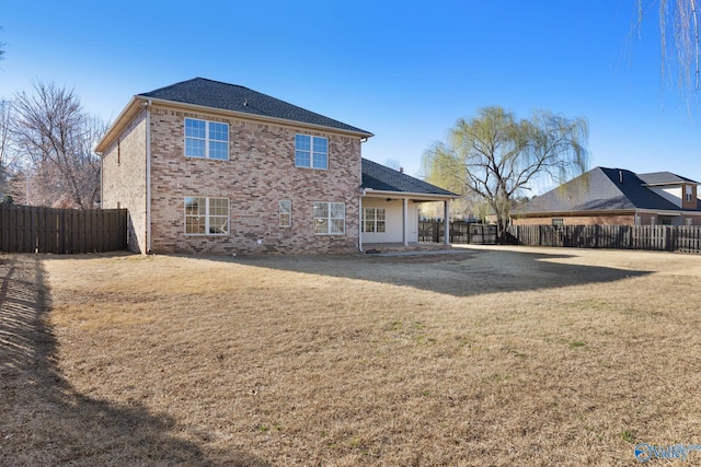 rear view of property with a yard, brick siding, and a fenced backyard