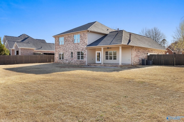 rear view of house featuring a lawn, brick siding, and fence private yard