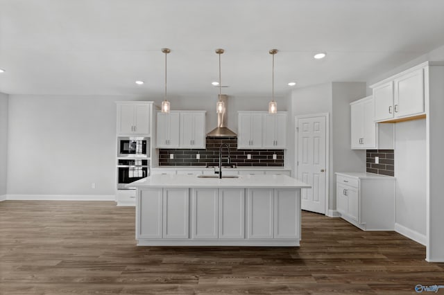 kitchen with a center island with sink, white cabinetry, pendant lighting, and stainless steel oven