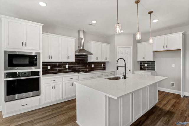 kitchen featuring white cabinetry, sink, black appliances, a center island with sink, and wall chimney exhaust hood