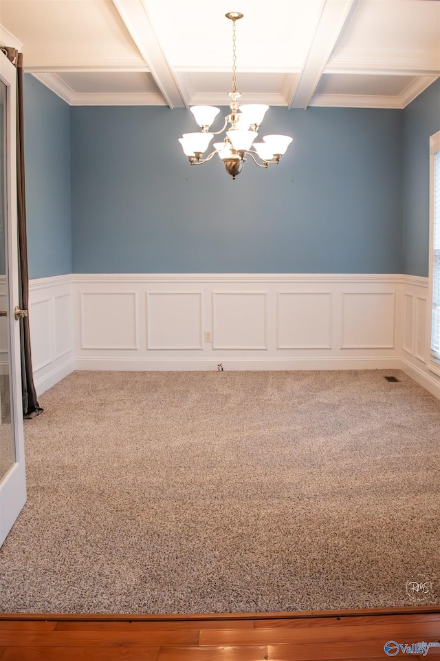 carpeted empty room with beam ceiling, crown molding, and a notable chandelier