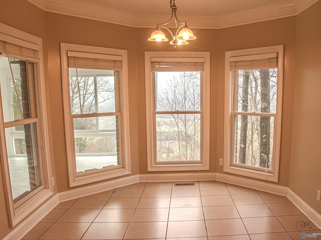 unfurnished dining area with tile patterned floors, ornamental molding, and an inviting chandelier