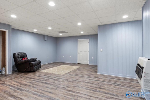 sitting room featuring a paneled ceiling, hardwood / wood-style flooring, and heating unit