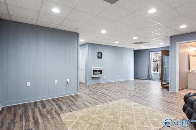 interior space featuring heating unit, a drop ceiling, and hardwood / wood-style floors