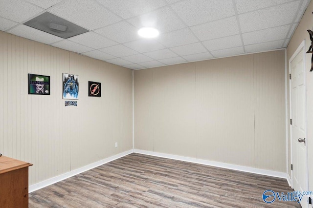 basement featuring a paneled ceiling and wood-type flooring