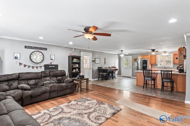 living room featuring ceiling fan, sink, crown molding, and light hardwood / wood-style flooring