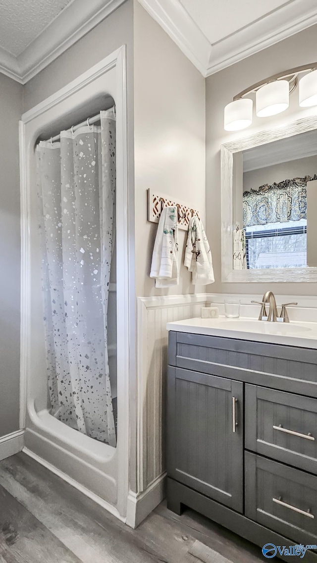 full bathroom featuring a shower with shower curtain, ornamental molding, wood finished floors, and vanity